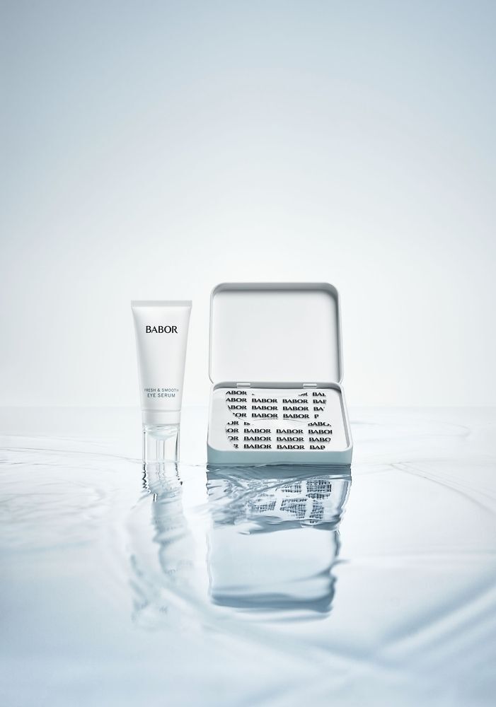 Un tube de sérum et une boîte ouverte avec des patchs pour les yeux. Sur l'eau. BABOR est écrit sur le tube.