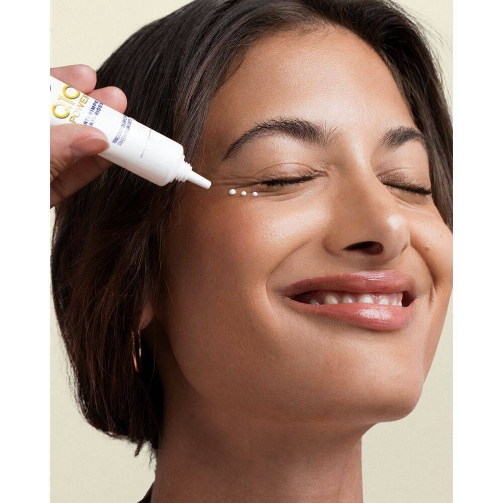 Femme aux yeux fermés, application du produit. Tube blanc avec logo bleu et jaune. Texte : Q10 Power, Anti-rides, Soin contour des yeux.