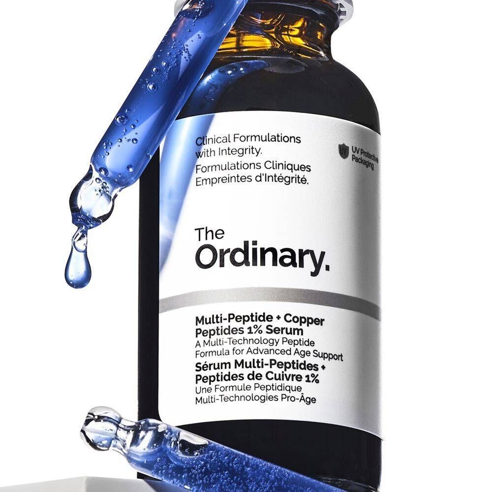 Flacon de sérum The Ordinary Multi-Peptide + Copper Peptides 1% avec un compte-gouttes qui laisse tomber du sérum.