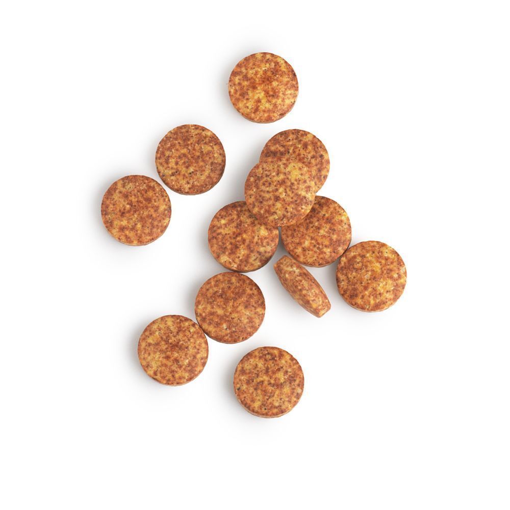 Plusieurs comprimés multivitaminés ronds et tachetés sur fond blanc.