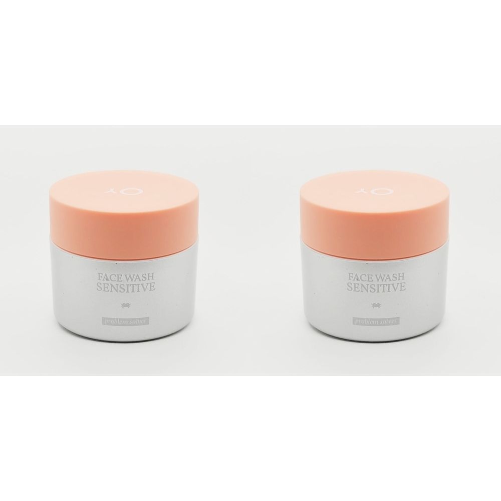 Deux pots avec couvercles orange. L'inscription "FACE WASH SENSITIVE" est visible.