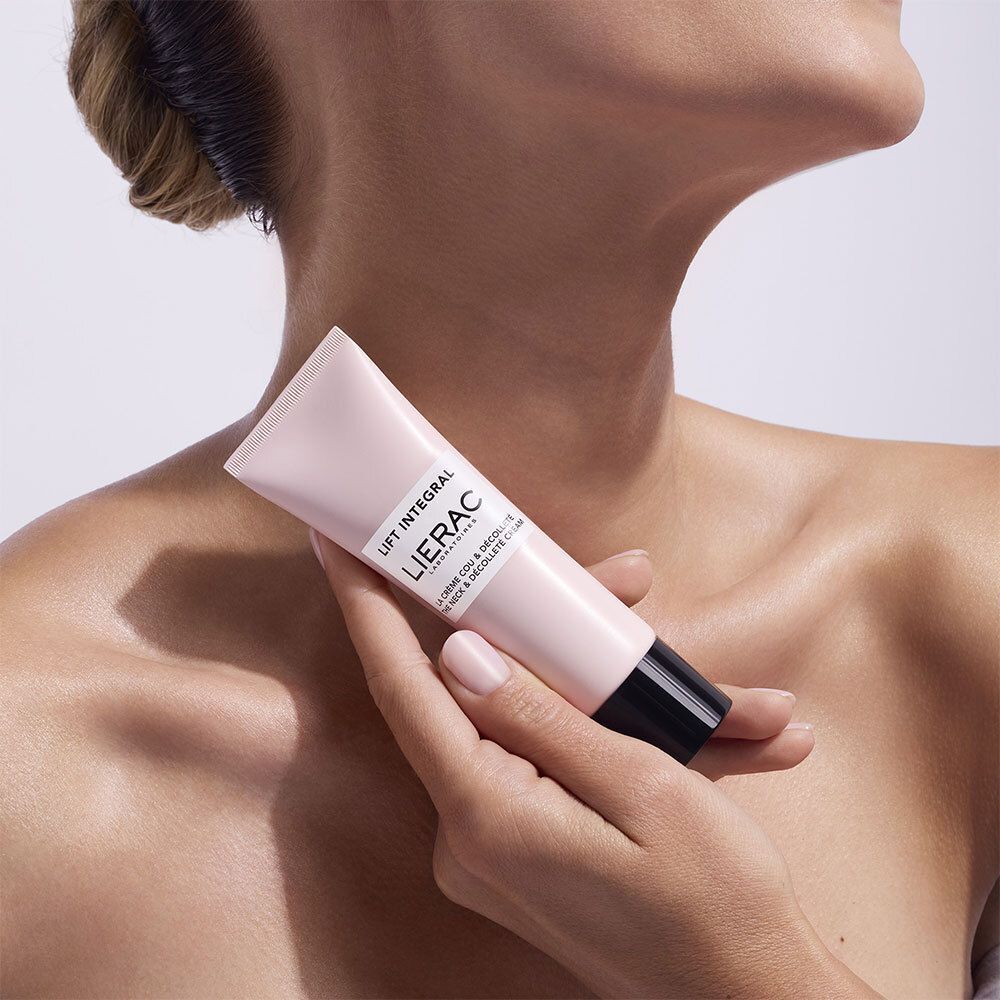 Personne tenant un tube rose avec bouchon noir. Inscription : Lierac Lift Integral, La Crème Cou & Décolleté.