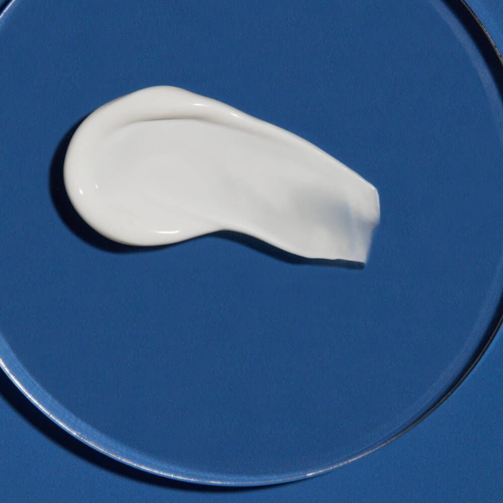 Produit crème blanc sur fond bleu. Forme de trait large. Sur surface lisse et ronde.