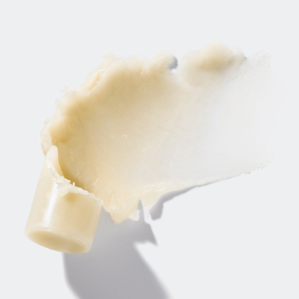 Étalement de texture crème sur fond blanc. Une partie du produit est visible.