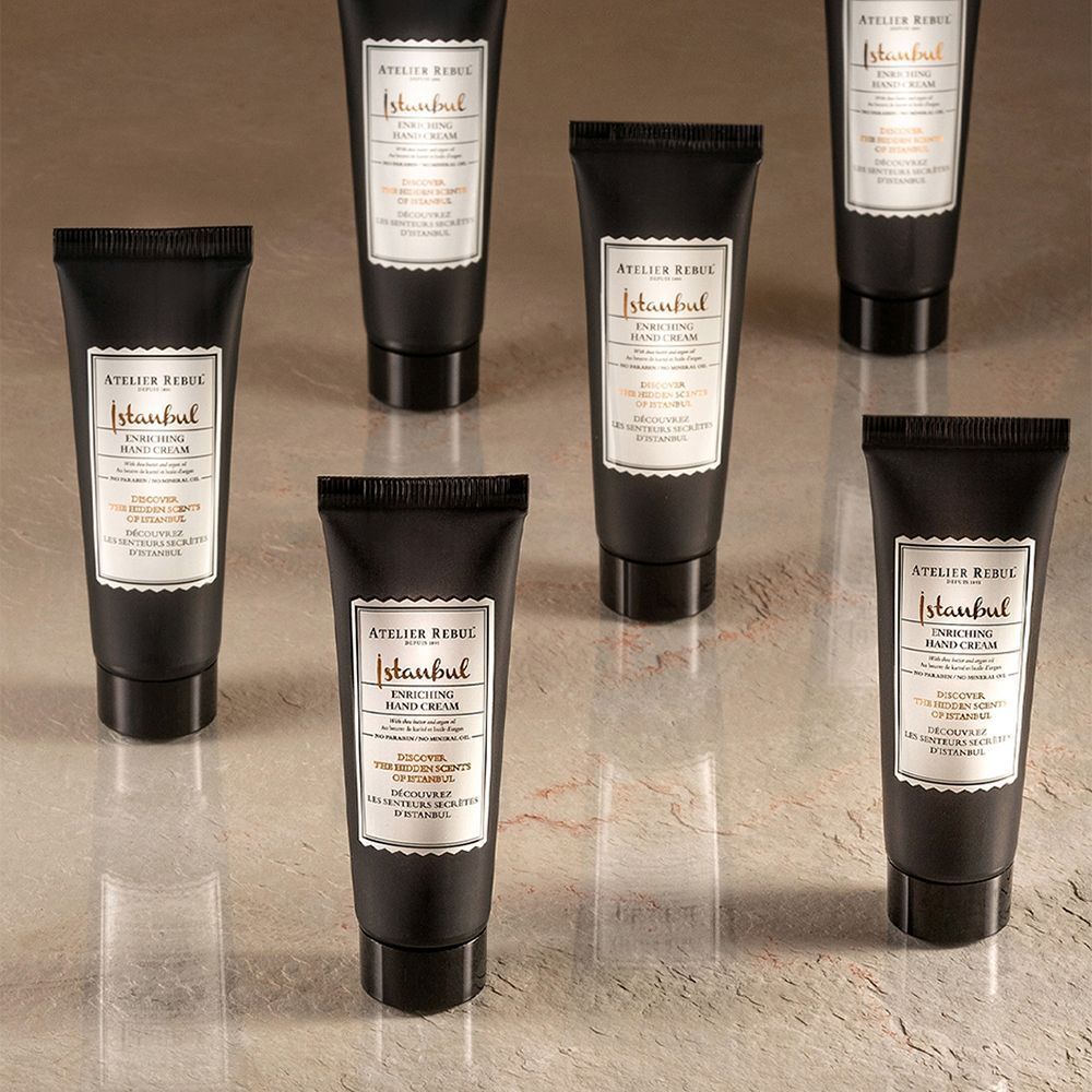Sept tubes noirs de crème pour les mains. Inscription : ATELIER REBUL Istanbul Enriching Hand Cream.