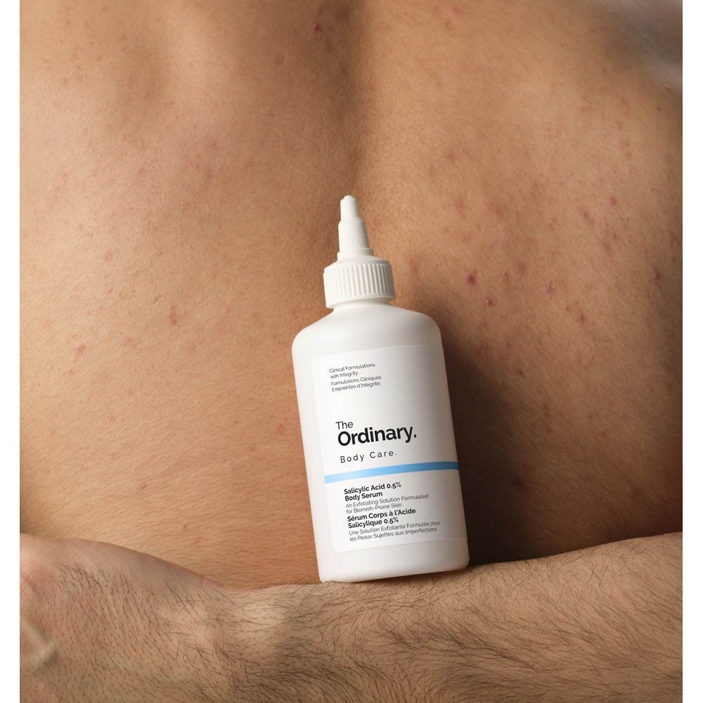 Flacon blanc devant un dos avec imperfections. Inscription: The Ordinary Body Care, Acide Salicylique 0,5 %.