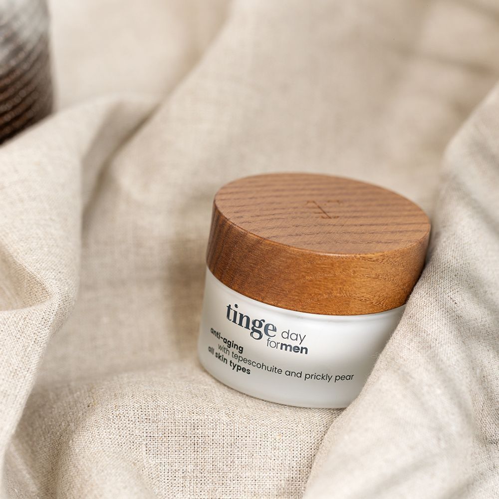 Pot avec couvercle en bois sur tissu. Inscription: Tinge day for men, anti-âge, avec tepescohuite et figue de barbarie, tous types de peau.