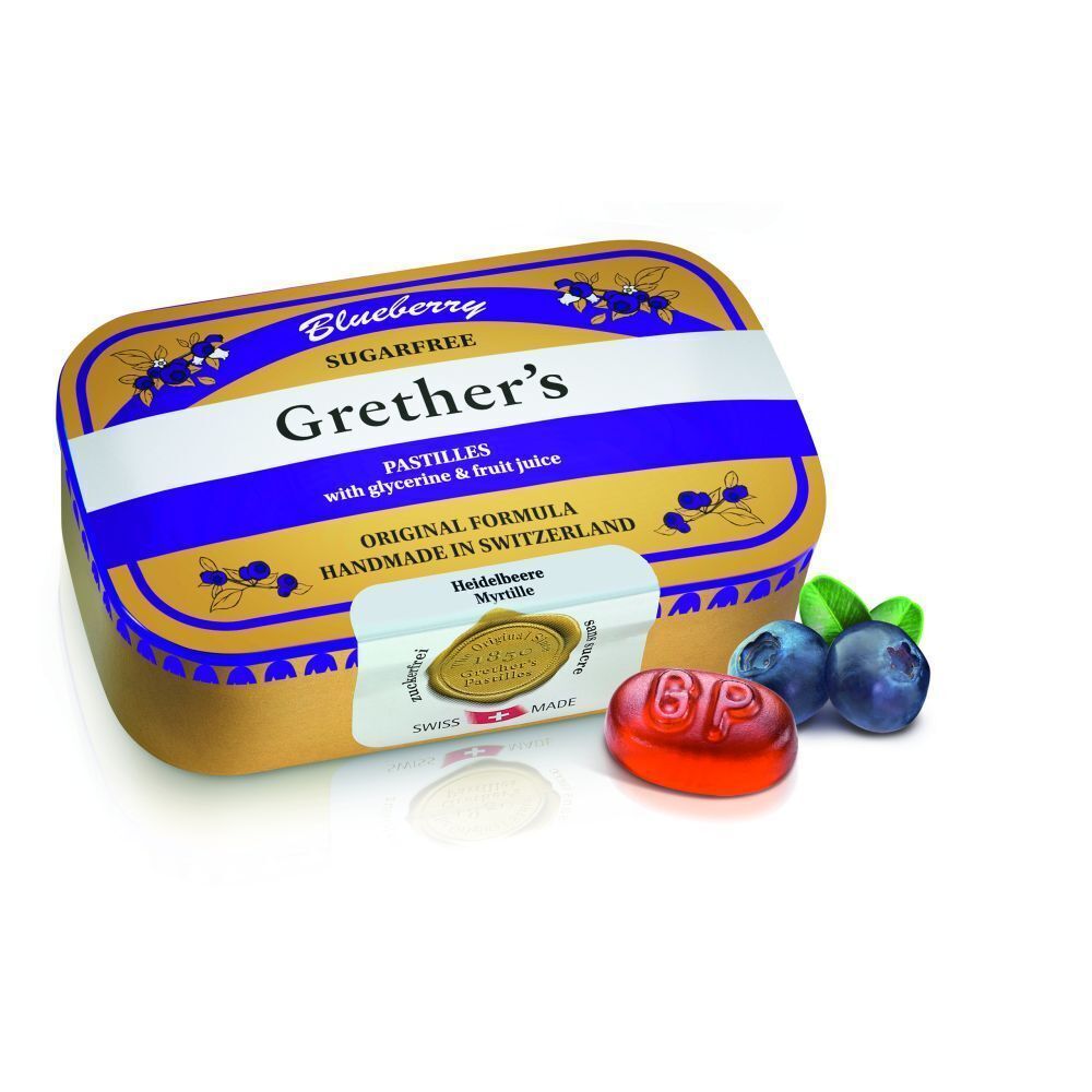 Boîte de pastilles dorée avec couvercle violet, une pastille et myrtilles. Inscription: Grether's Pastilles Blueberry Sans Sucre.