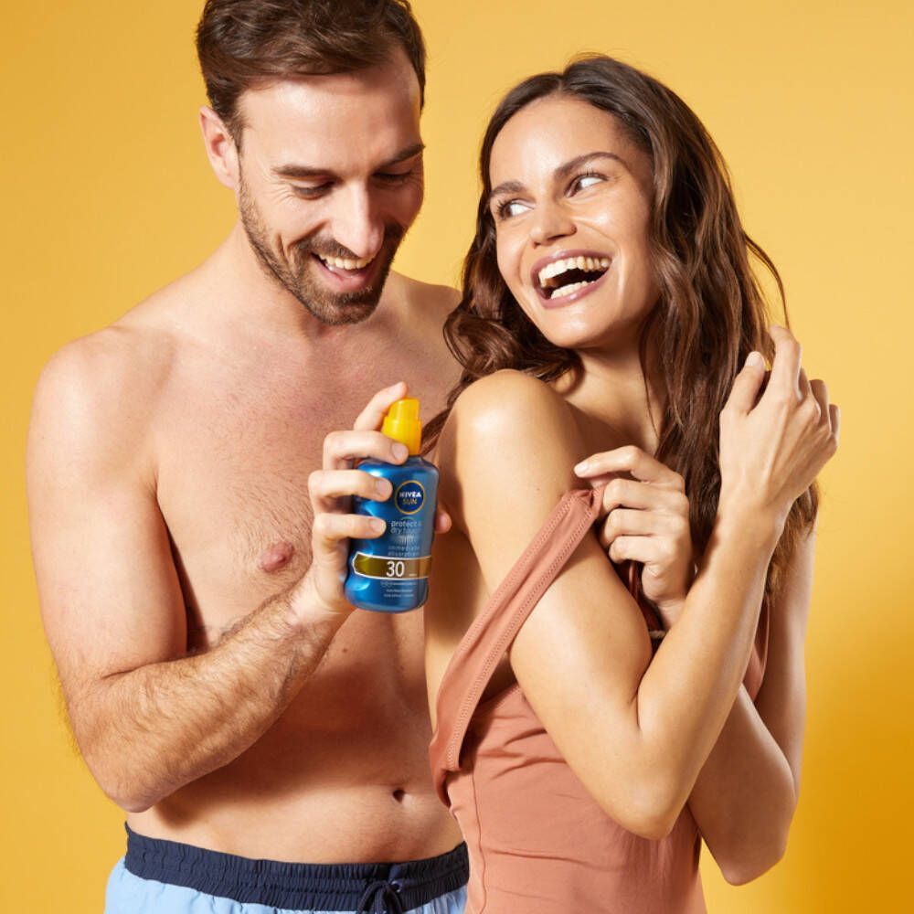 Homme et femme avec Nivea Sun Protect & Dry Touch Brume Solaire SPF30. L'homme tient le flacon, la femme sourit.