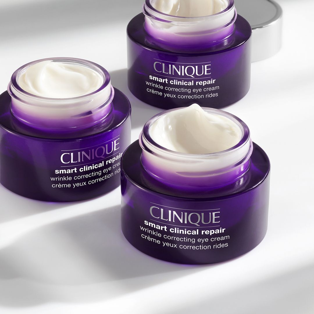Trois pots de crème, partiellement ouverts. On peut lire "CLINIQUE Smart Clinical Repair" et "crème yeux".