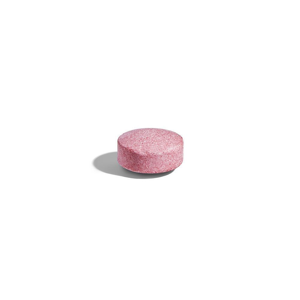 Un comprimé rond rose. Sur fond blanc.
