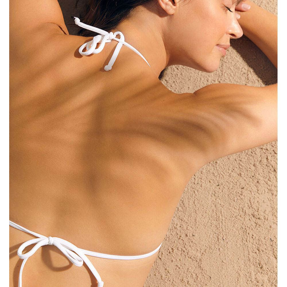 Dos d'une femme à la plage. Haut de bikini blanc.