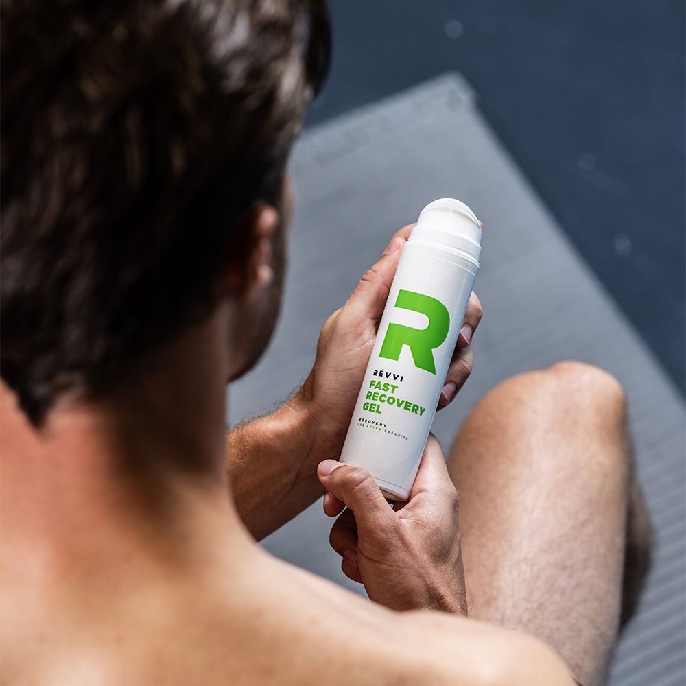 Homme tenant un flacon blanc avec logo "R" vert et inscription RÉVVI FAST RECOVERY GEL.