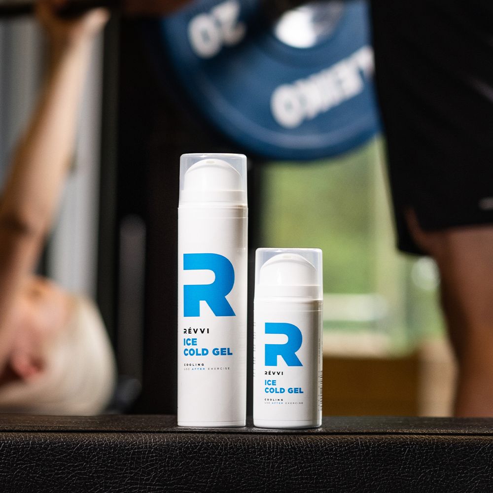 Deux flacons blancs avec logo "R" bleu. Texte : RÉVVI ICE COLD GEL. En arrière-plan : personne soulevant des poids.
