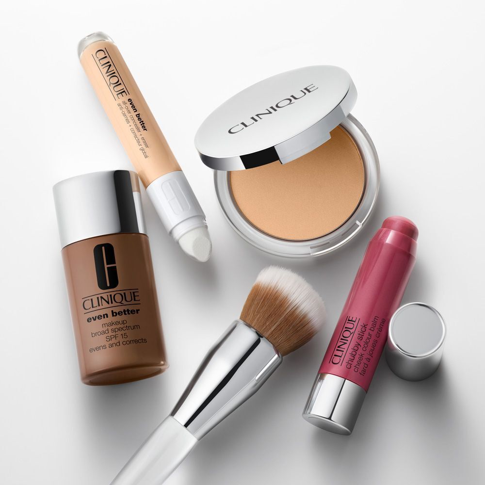 Divers produits cosmétiques, dont une poudre compacte. Produits de CLINIQUE. Sur fond blanc.