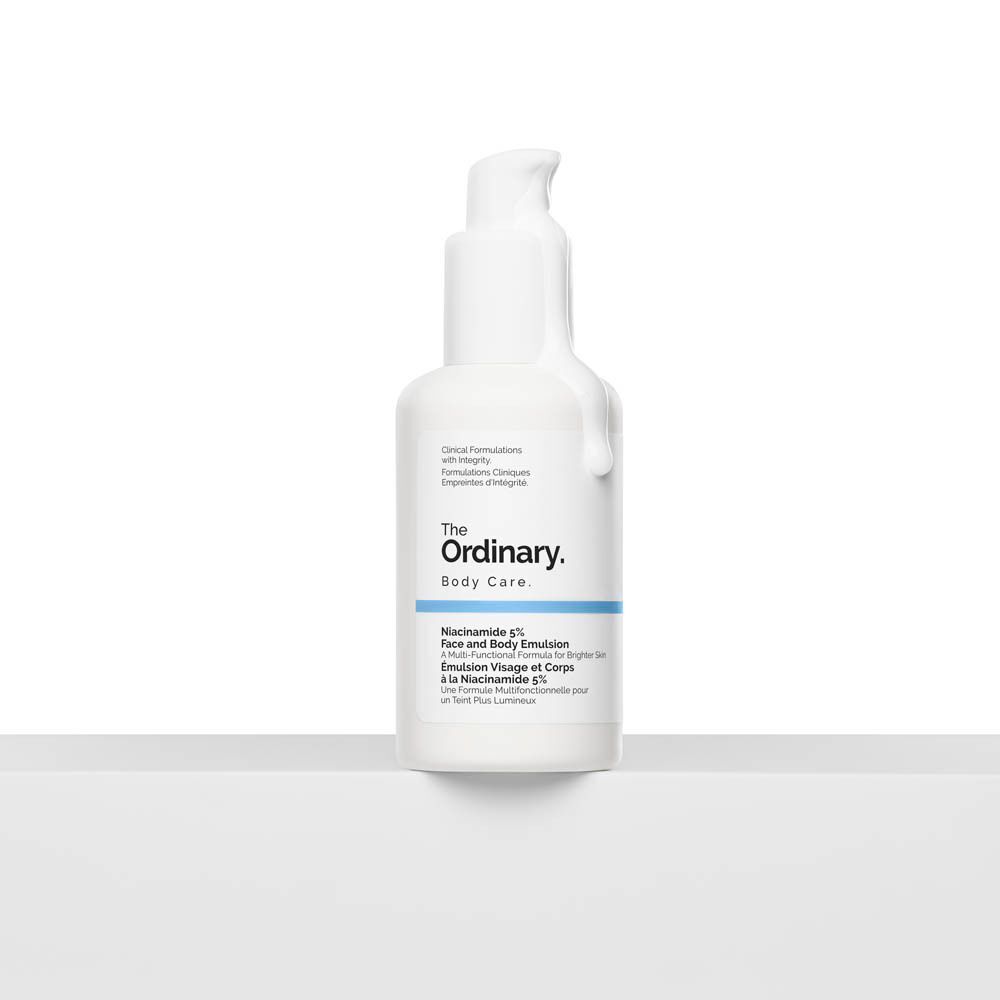 Flacon blanc The Ordinary Body Care. Inscription : Niacinamide 5% Face and Body Emulsion. Produit sur surface blanche.
