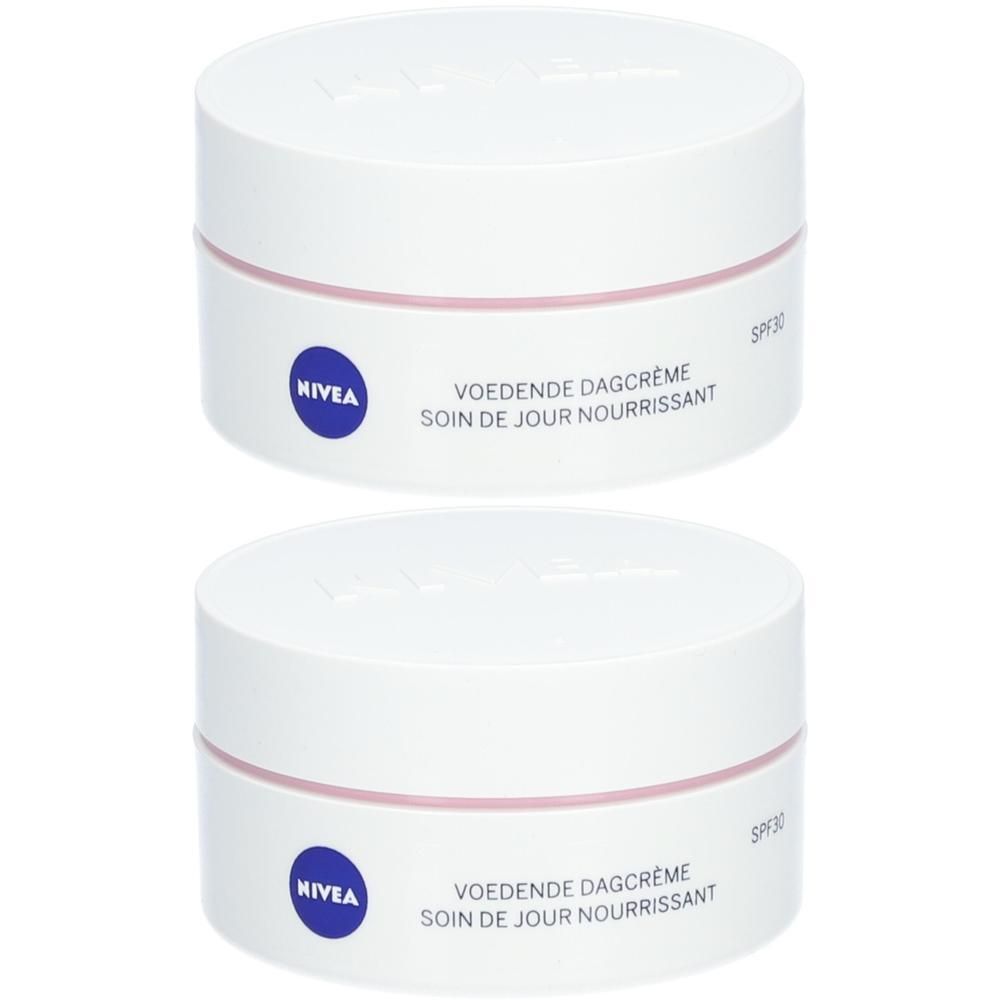 Deux pots blancs avec bande rose et texte bleu. Inscription: Voedende Dagcrème, Soin de jour Nourrissant, Nivea.
