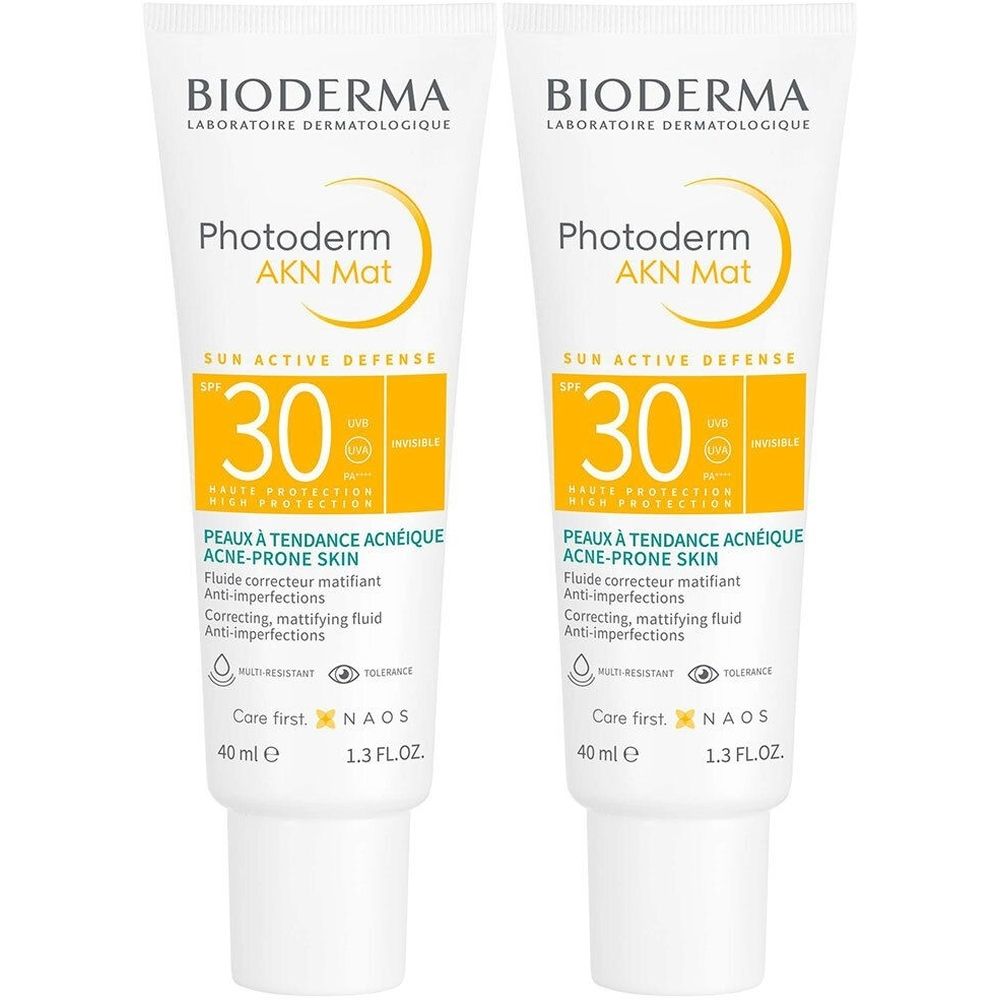 Deux tubes de Bioderma Photoderm AKN Mat. Tubes blancs avec accents jaunes. Texte: Photoderm AKN Mat, SPF 30, peaux à tendance acnéique.