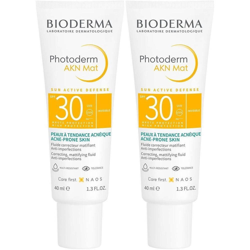 Deux tubes de BIODERMA Photoderm AKN Mat SPF30. Tubes blancs avec accents jaunes. Texte : SPF 30, Peaux à tendance acnéique.