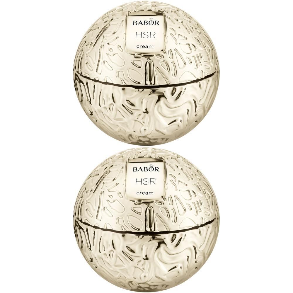 Deux pots de crème dorés avec l'inscription Babor HSR cream. Les pots ont une forme sphérique avec un motif en relief.