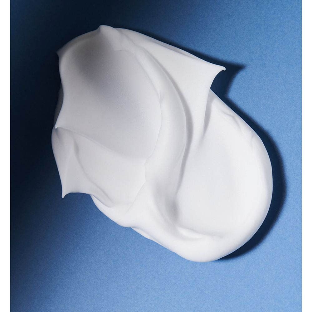 Gros plan de crème à raser blanche sur fond bleu. La crème a une forme ondulée.