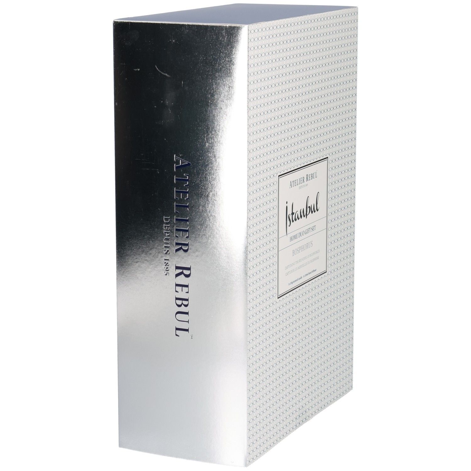 Vue latérale d'une boîte cadeau avec finition argentée métallique et inscription verticale Atelier Rebul.