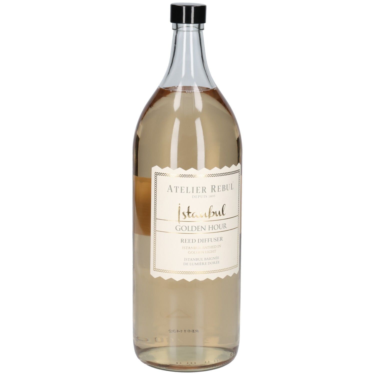 Grande bouteille en verre transparent avec bouchon noir. Étiquette avec texte doré : Atelier Rebul Istanbul Golden Hour Reed Diffuser.