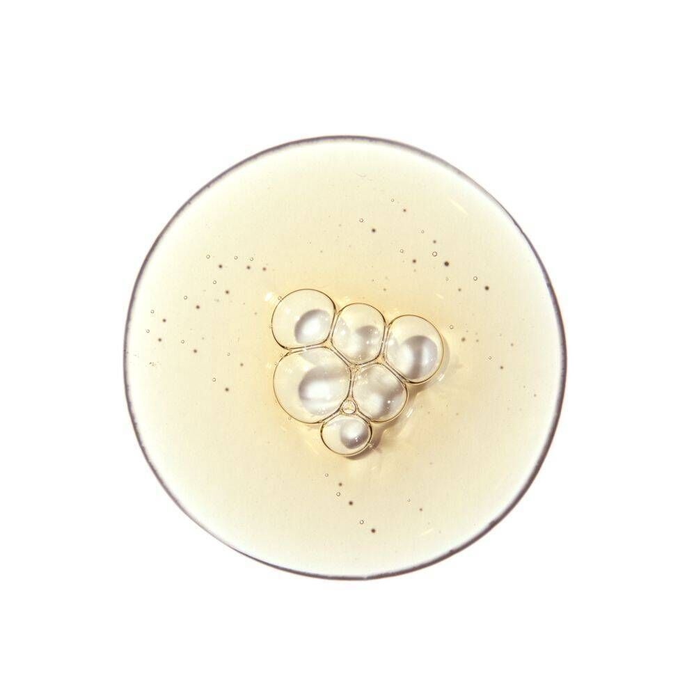 Gouttes de la solution avec de petites bulles et des particules scintillantes sur une surface ronde.