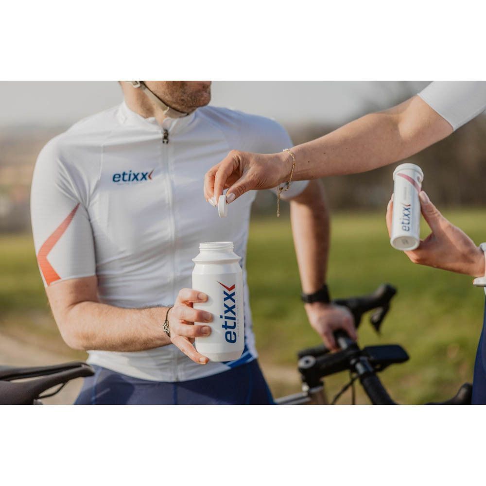 Un sportif prépare une boisson avec les comprimés effervescents Etixx Isotonic Drink Tabs Citron. Bouteille Etixx visible.