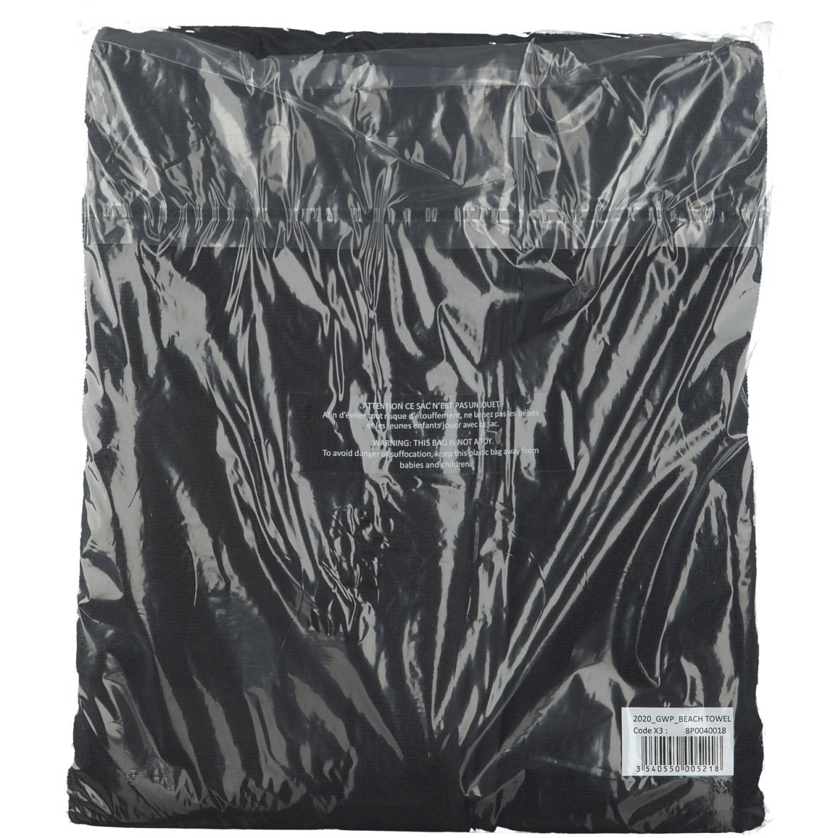Serviette de plage noire dans un emballage plastique transparent. Étiquette avec code-barres et informations.