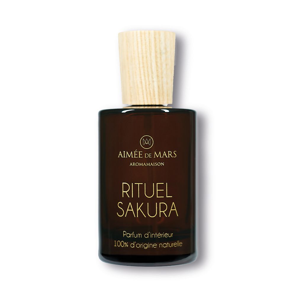 Flacon en verre brun avec bouchon en bois. Inscription: RITUEL SAKURA, Parfum d'intérieur, 100% d'origine naturelle. Marque visible.
