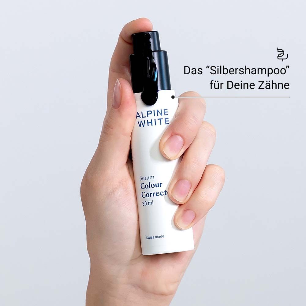 Main tenant le flacon de sérum. Texte : ALPINE WHITE, Serum Colour Corrector, 30 ml. Bouchon noir.