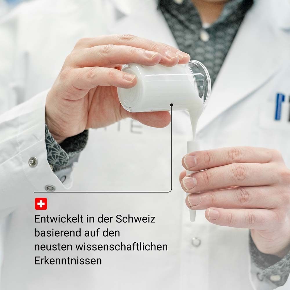 Personne verse du sérum dans un récipient. Environnement de laboratoire. Texte : Développé en Suisse.