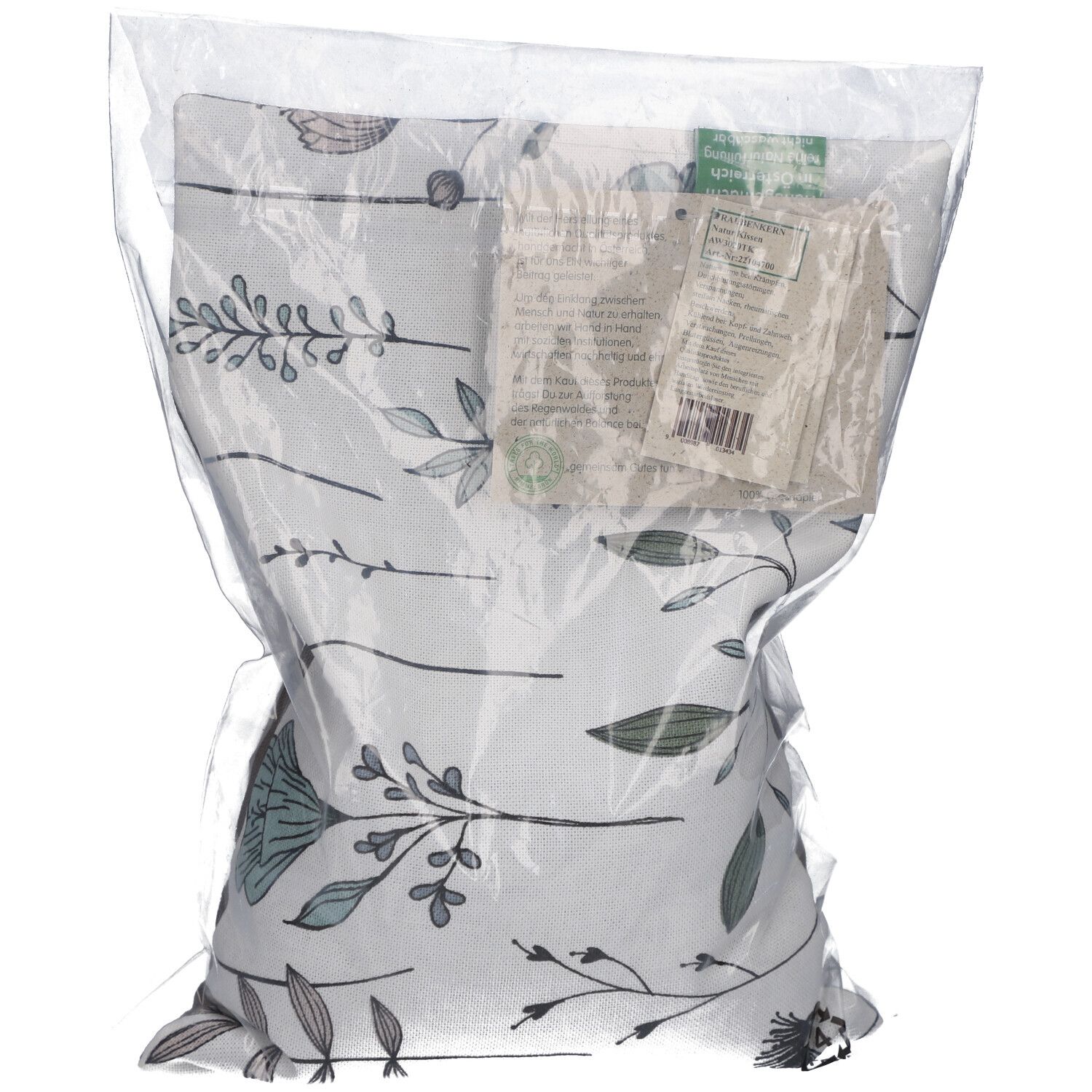Coussin floral emballé. Motif de fleurs et feuilles grises et bleues sur fond blanc, dans un emballage plastique transparent.