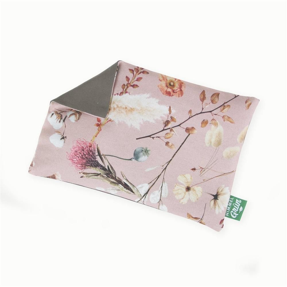 Coussin floral rectangulaire, imprimé de fleurs sur fond rose. Dos gris. Étiquette verte avec texte.