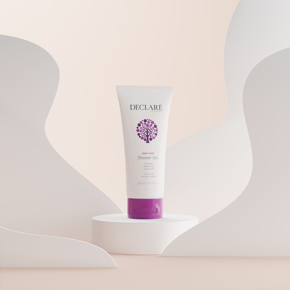 Tube blanc avec bouchon violet sur socle. Logo DECLARÉ et nom du produit Shower Gel. Fond avec formes.