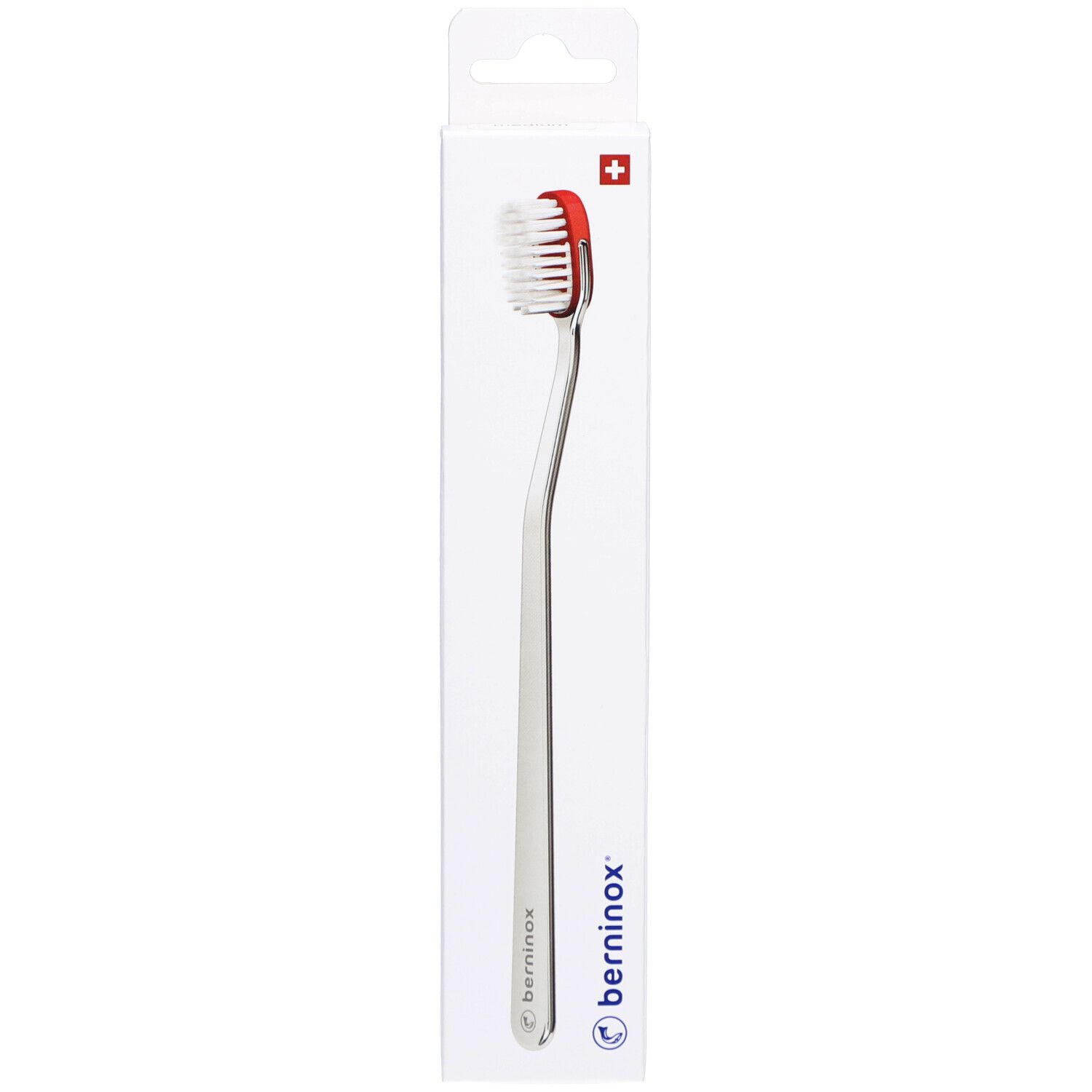 Brosse à dents avec tête rouge et manche argenté, dans un emballage blanc. Croix suisse en haut.