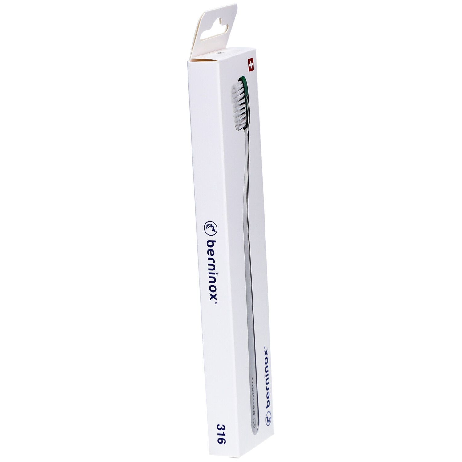 Brosse à dents dans son emballage. Manche argenté, tête verte. Emballage avec logo et croix suisse. Vue en angle.