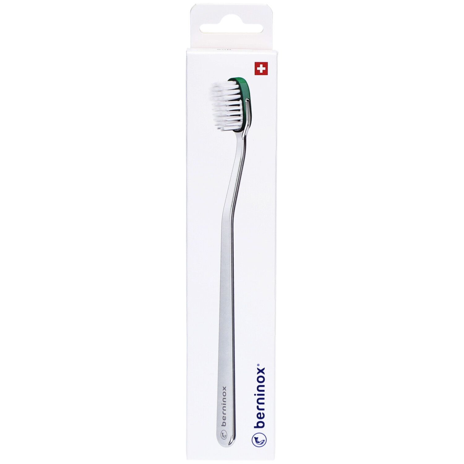 Brosse à dents dans son emballage. Manche argenté, tête verte avec poils blancs. Emballage avec logo et croix suisse.