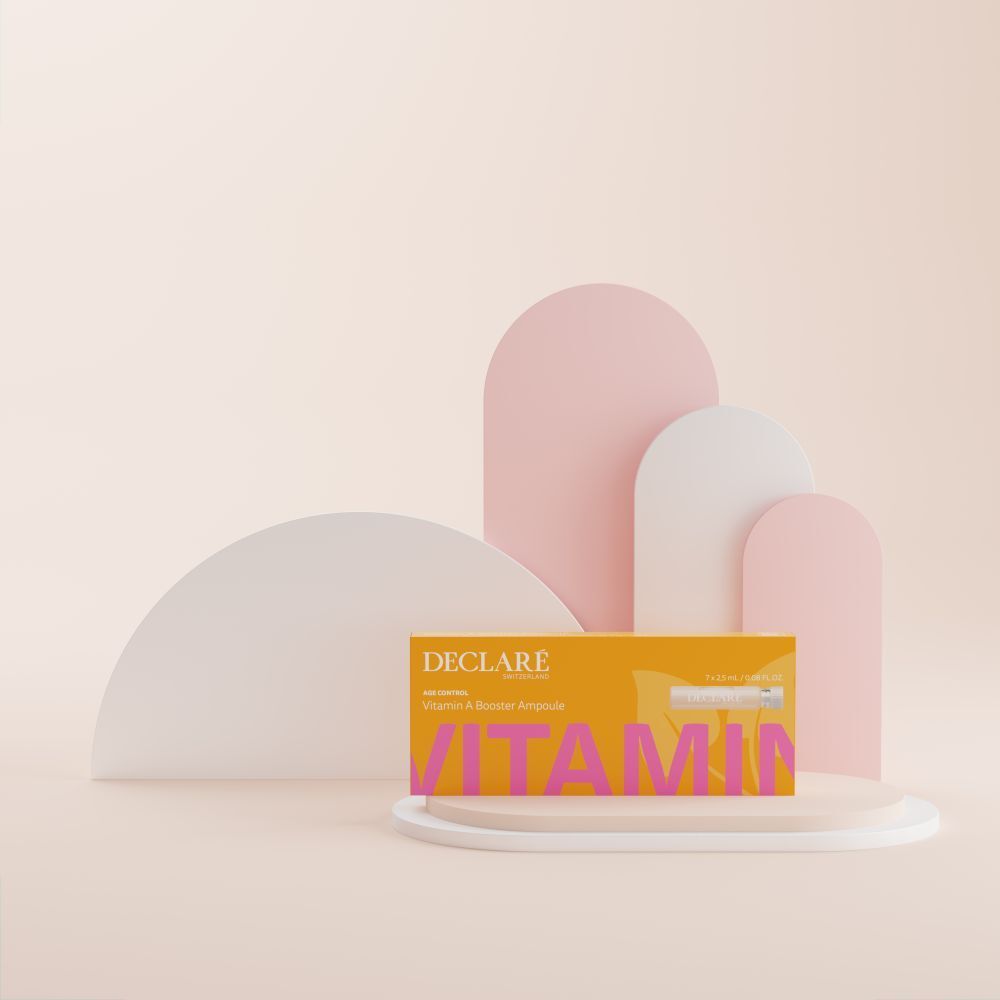 Boîte jaune DECLARÉ Vitamin A Booster Ampoule sur socle. Inscription rose "VITAMIN". Fond avec formes.