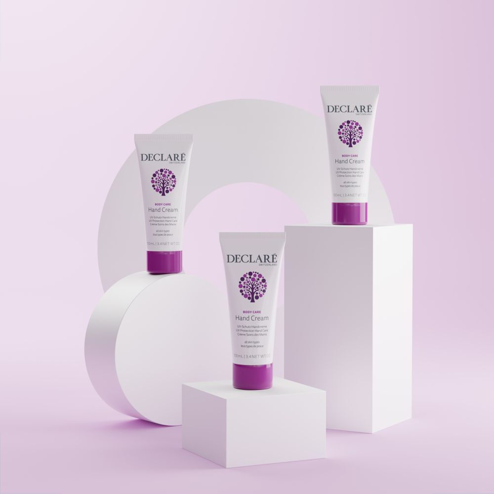 Trois tubes, bouchons violets sur socles. DECLARÉ, Hand Cream, UV-Schutz Handcreme. Fond avec formes.