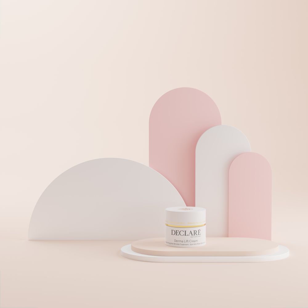 Pot blanc avec couvercle doré sur socle. Inscription : DECLARÉ, Derma Lift Cream. Fond : abstrait.