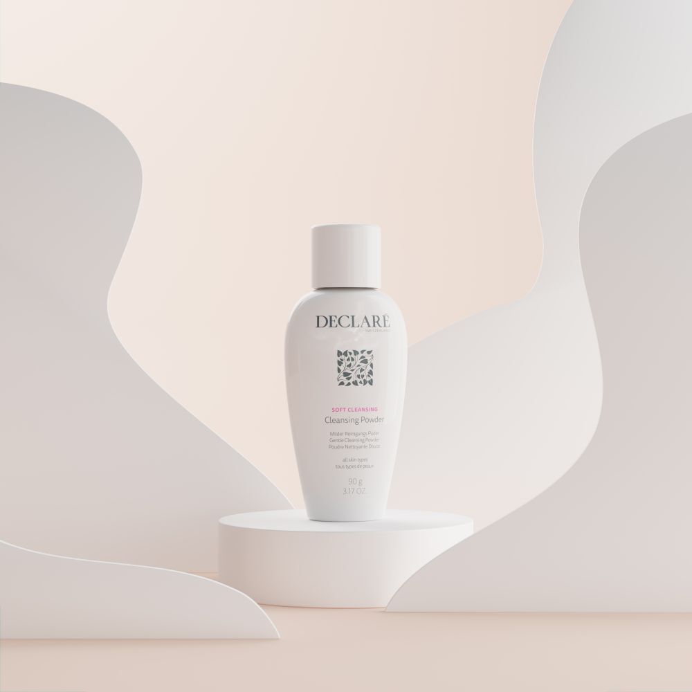DECLARÉ Soft Cleansing Poudre sur socle. Produit blanc, logo, nom, informations. Fond avec formes.