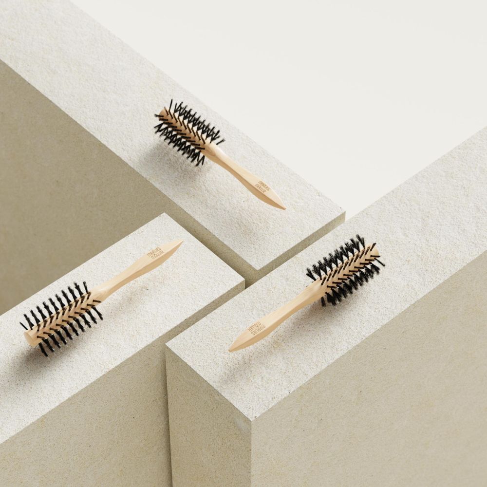 Trois brosses à cheveux rondes sur des blocs blancs. Manche en bois, poils noirs.