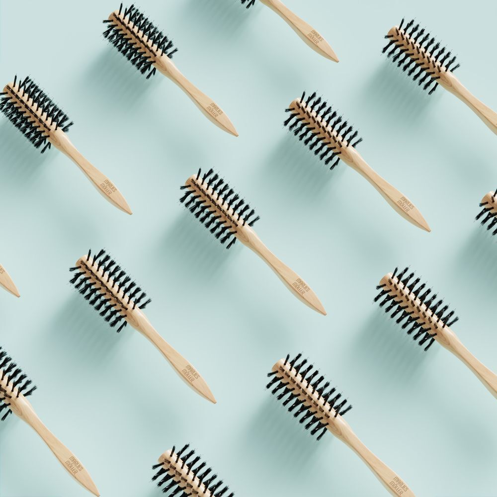 Motif de brosses à cheveux rondes sur fond bleu clair. Manche en bois, poils noirs.