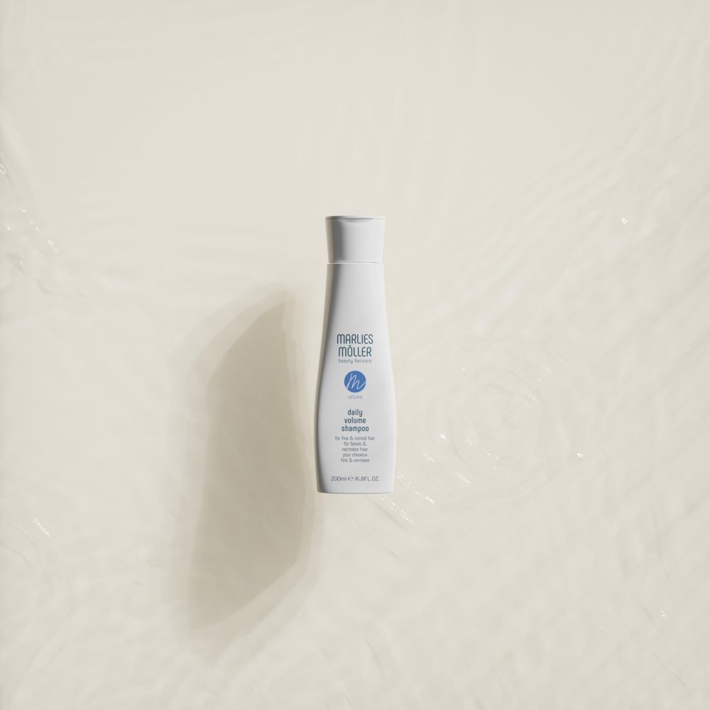 Flacon de shampooing blanc sur fond crème. Inscription: Marlies Möller, Volume Daily Volume Shampoo. 200ml.