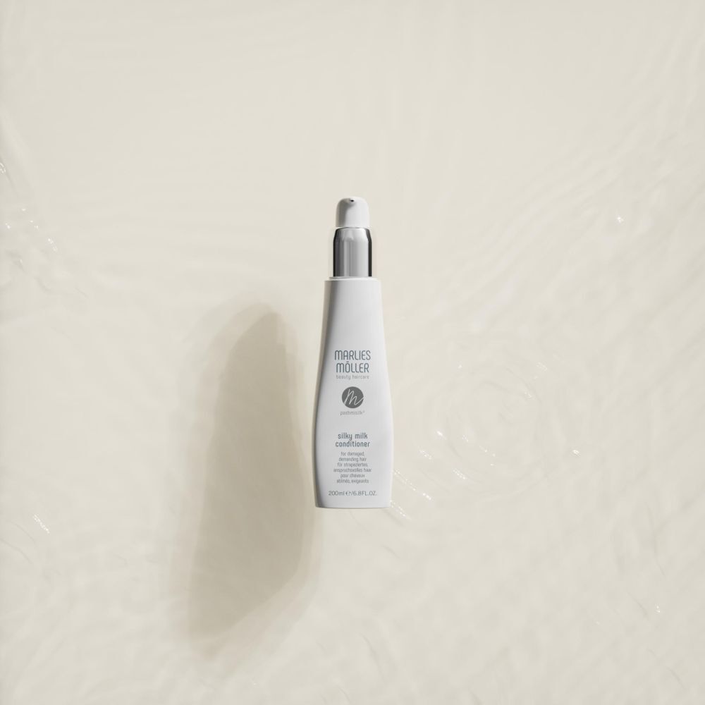 Flacon blanc avec pompe. Inscription: Marlies Möller, Pashmisilk Silky Milk Conditioner. Sur l'eau.