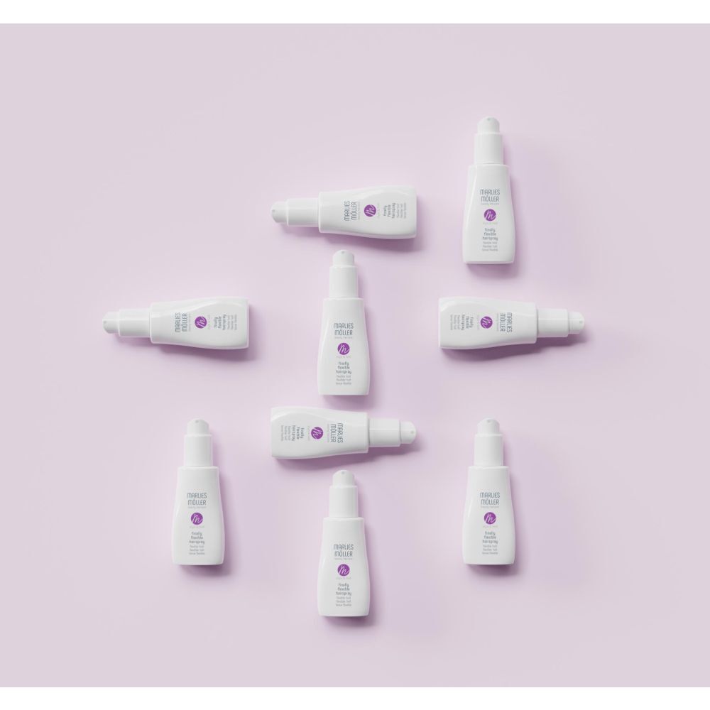Plusieurs bouteilles de spray Marlies Möller Finally Flexible sur fond rose.