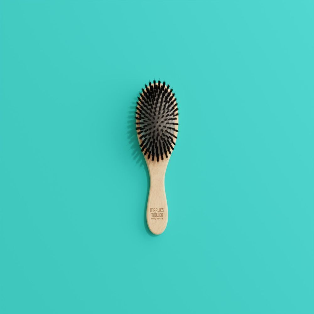 Brosse à cheveux ovale, manche en bois, soies noires. Sur fond turquoise.