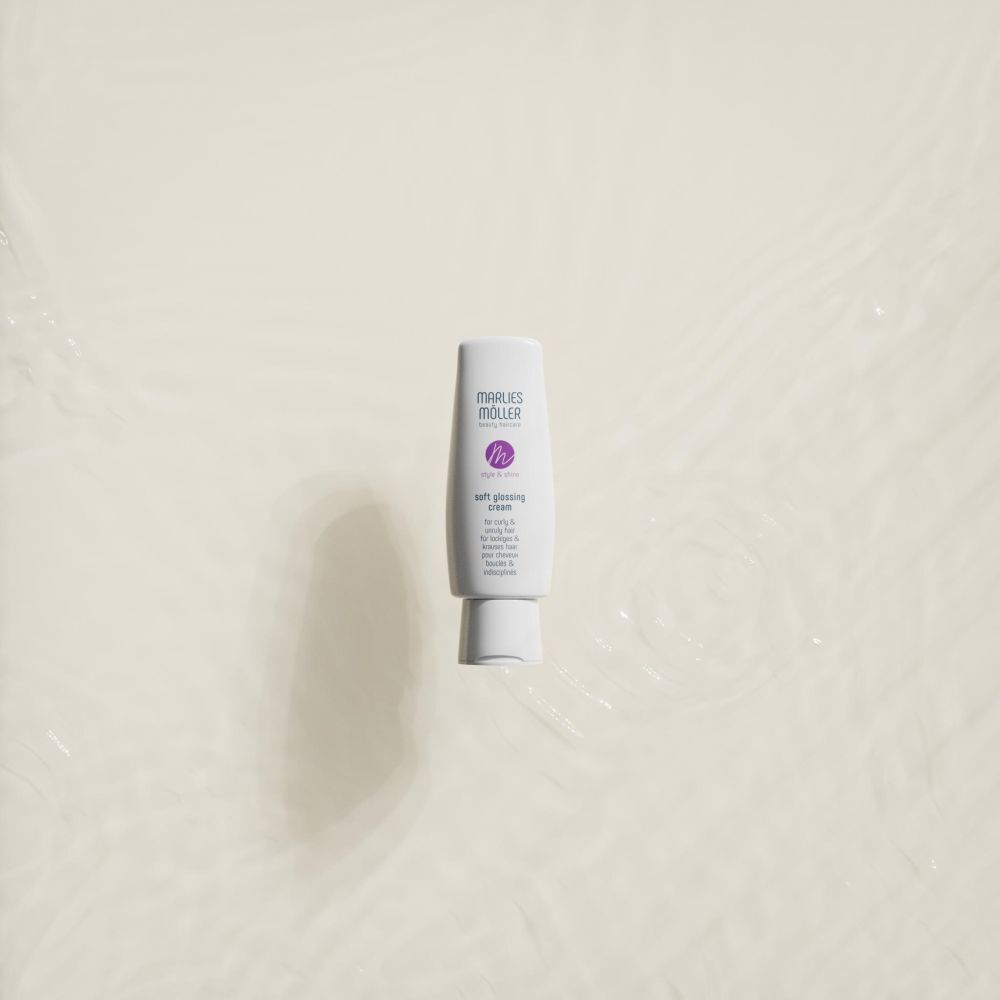 Tube blanc, Marlies Möller Soft Glossing Cream, sur fond clair. Le produit semble flotter dans l'eau.